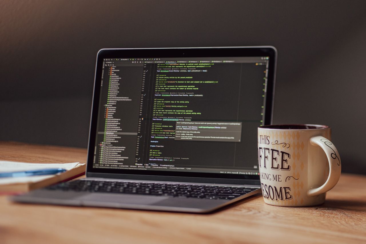 Home Laptop displaying code editor with coffee mug on desk, perfect for tech themes.